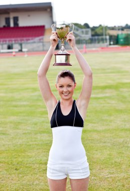 Cheerful female athlete holding a trophee clipart
