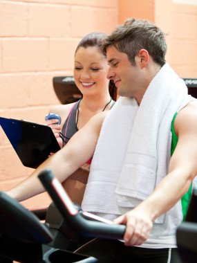 Handsome male athlete exercising on a bicycle with his personal clipart