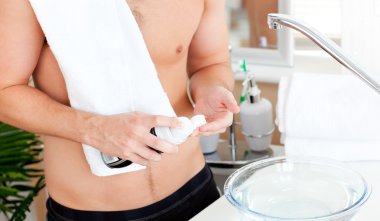 Close-up of a young muscular man ready to shave in the bathroom clipart