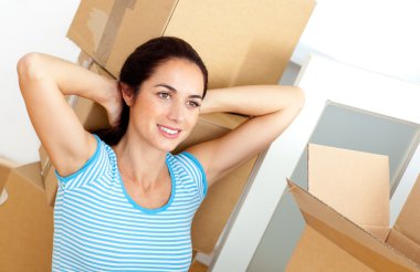 Relaxed young woman sitting on the floor after unpacking cardboa clipart