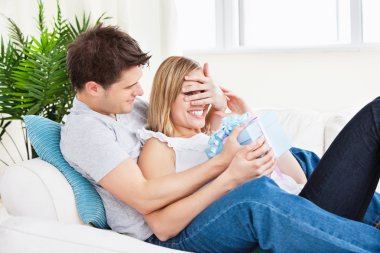 Young couple lying on the sofa with a present clipart