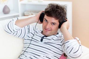 Funny man listening music with headphones on sitting in his livi clipart