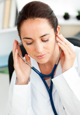 Concentrated hispanic doctor using a stethoscope clipart