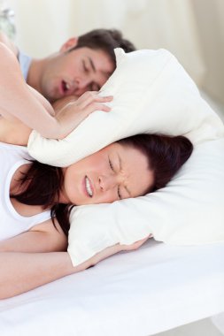 Young woman disturbed by the snores of her boyfriend in the bedr clipart