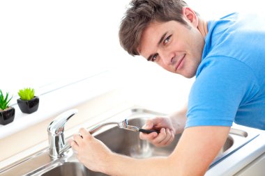 Young man repairing a kitchen sink clipart