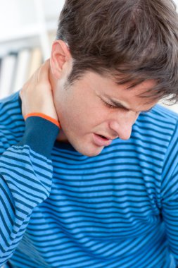 Caucasian man having a neckache in the living-room clipart