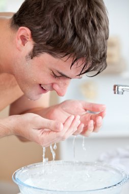 Smiling caucasian man spraying water on his face after shaving i clipart