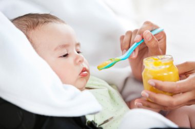 Close-up of a mother giving food to her adorable baby clipart