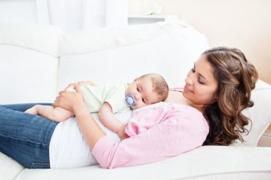 Young mother taking care of her adorable baby clipart