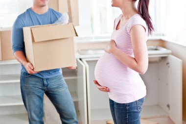 Close-up of a pregnant woman talking to her husband who is holdi clipart