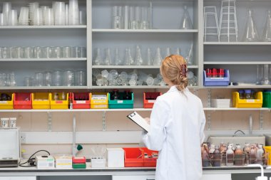 Serious female scientist writing on her clipboard clipart