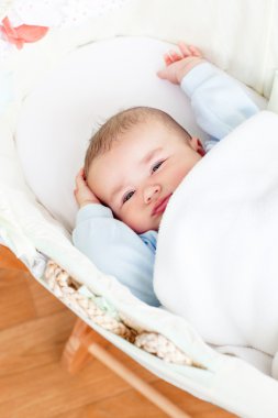 Cute baby boy waking-up lying in his cradle at home clipart