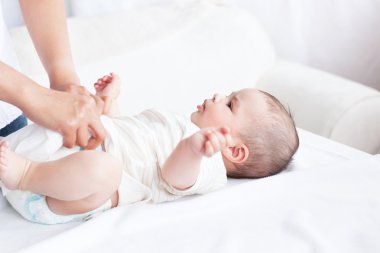 Close-up of a young mother changing the nappy of her baby lying clipart