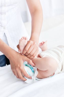 Close-up of an attentive mother taking off the dirty nappy of he clipart