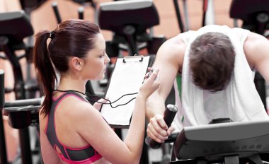 Female coach using a chronometer while man is pedaling on a bicy clipart