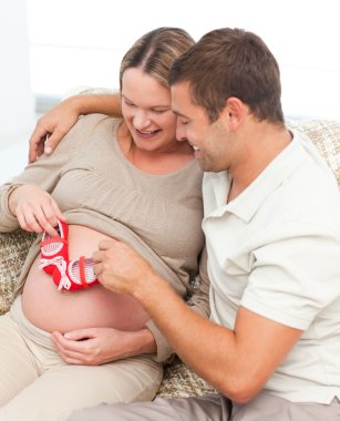 Cute man playing with baby shoes on his wife's clipart