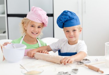 Happy brother and sister preparing a dough standing in the kitch clipart