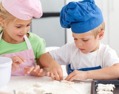 Young brother and sister kneading a dough to make cakes clipart