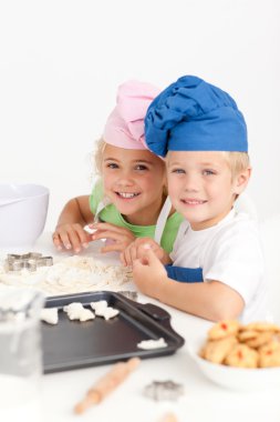 Two little chefs preparing cookies in the kitchen clipart