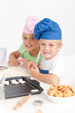 Adorable siblings kneading together a dough in the kitche clipart