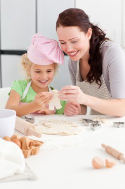 Cheerful mother and daughter making cookies in form of a man clipart