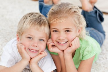 Brother and sister looking at the camera on the floor clipart