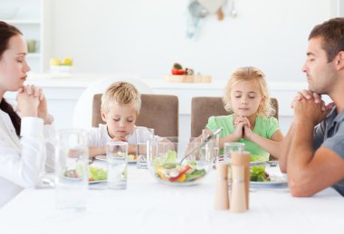 Portrait of a family praying together during the lunch clipart