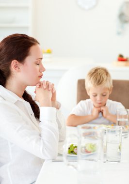 Concentrated mother and son praying during the lunch clipart