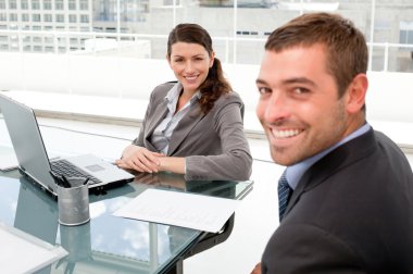 Happy businesspeople working together on a laptop during a meeti clipart