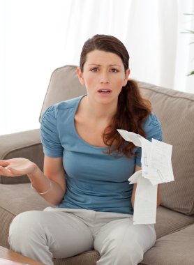 Worried woman misunderstanding her bills sitting in the living r clipart