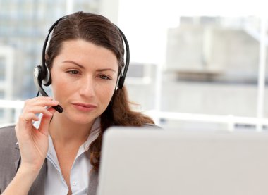 Concentrated businesswoman working on her laptop while calling clipart