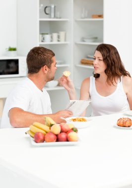 Cute woman giving bread to his husband during breakfast in the k clipart