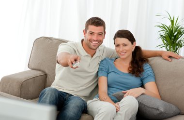 Happy man watching television with his girlfriend sitting on the clipart