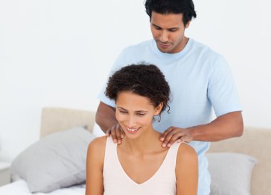 Handsome man doing a massage to his beautiful wife on their bed clipart