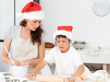 Mother and son preparing Christmas biscuits together clipart