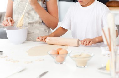 Close up of mother and son preparing a dough together clipart