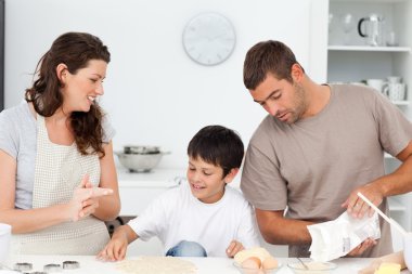 Caucasian family cooking biscuits together in the kitchen clipart