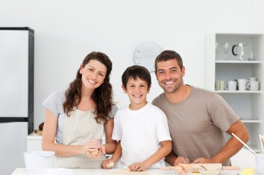 Portrait of a happy family preparing biscuits together clipart