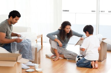 Happy family packing dishes together in their living-room clipart