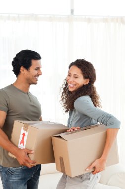 Lovely couple holding cardboards in their living-room clipart