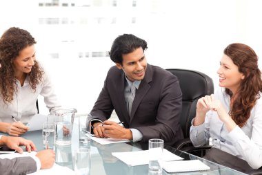 Businessman and businesswomen talking together around a table clipart