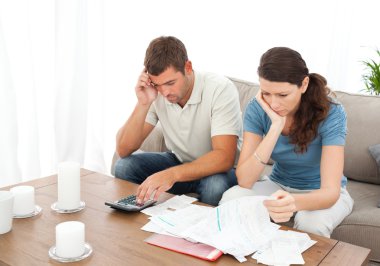Desperate couple doing their accounts sitting on the sofa clipart