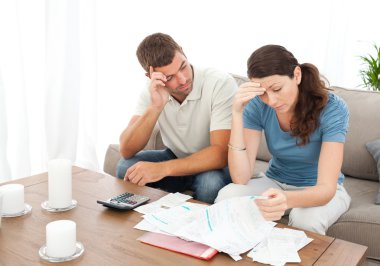 Worried couple doing their accounts in the living room clipart