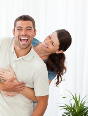 Joyful couple laughing topgether in the living-room clipart