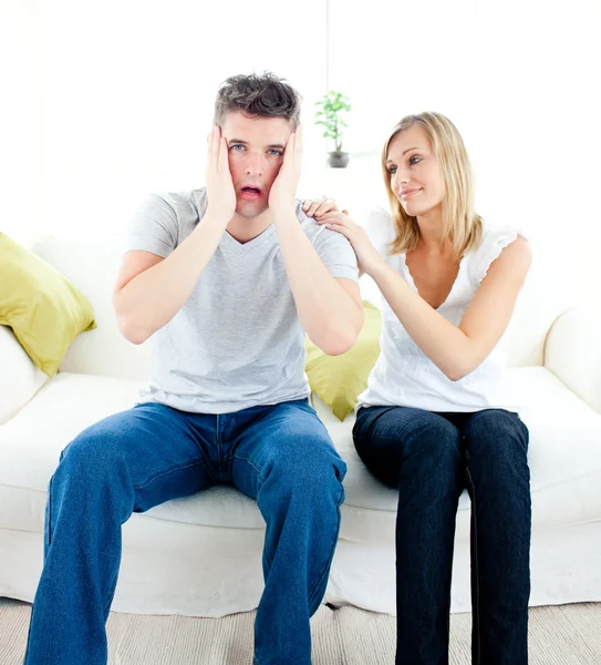 Homem chocado sentado no sofá com sua namorada — Fotografia de Stock