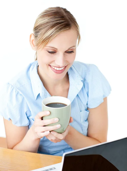 Smiling businesswoman drinking coffee using her laptop — Stock Photo, Image