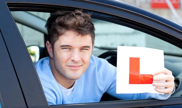 Positvie joven conductor masculino sosteniendo un signo L —  Fotos de Stock