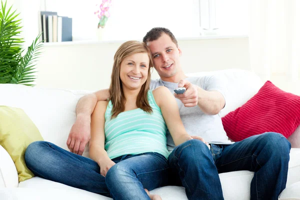 Hombre cariñoso abrazando a su novia mientras ve la televisión —  Fotos de Stock