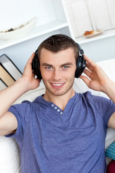 Relaxed young man listening to music looking at the camera — Stock Photo, Image