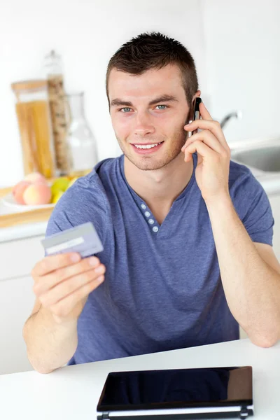 Ελκυστικό νεαρό άνδρα που μιλάει στο τηλέφωνο κρατώντας μια κάρτα εξετάζοντας — Φωτογραφία Αρχείου